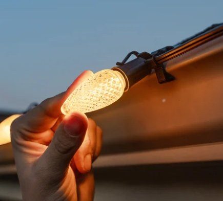 C9 faceted LED bulb clipped to a gutter, glowing warm white
