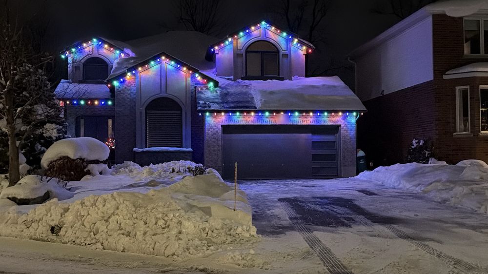 Home with three gables and the garage roofline in multicolour lights
