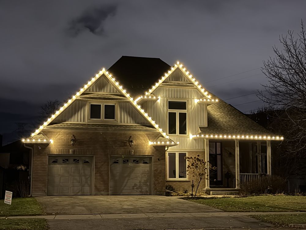 Brick home with two steep gables outlined in warm white lights